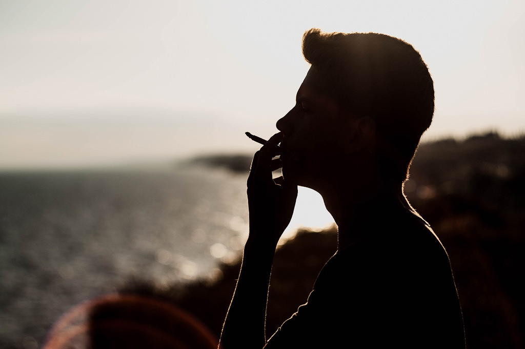 Ein Mann raucht draußen Cannabis bei Sonnenuntergang.