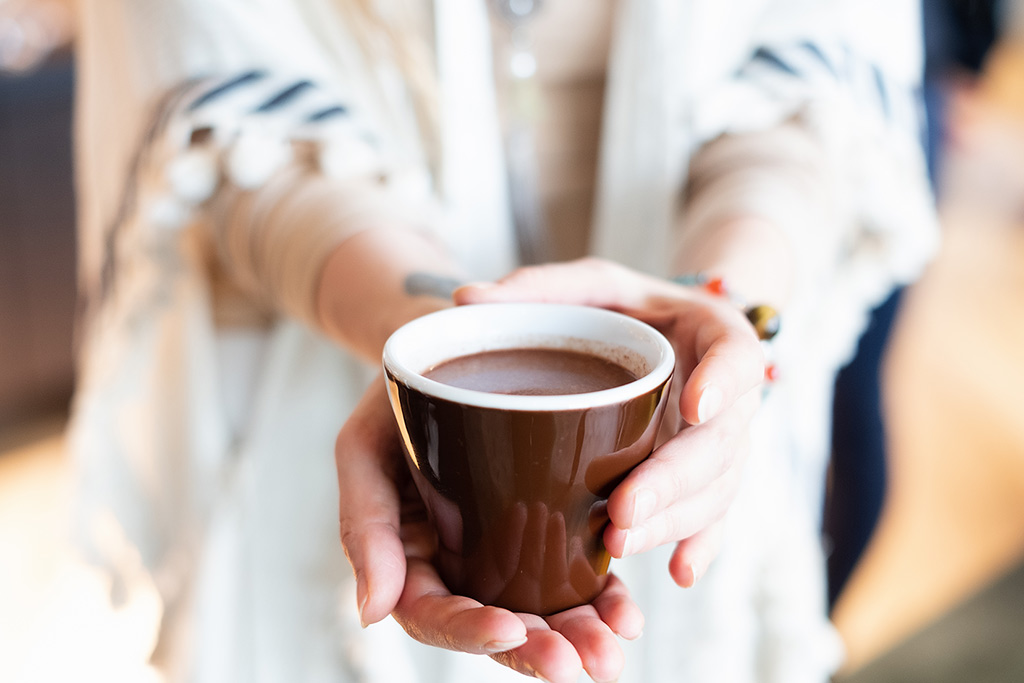 Eine Frau bietet eine Tasse heiße Schokolade an.